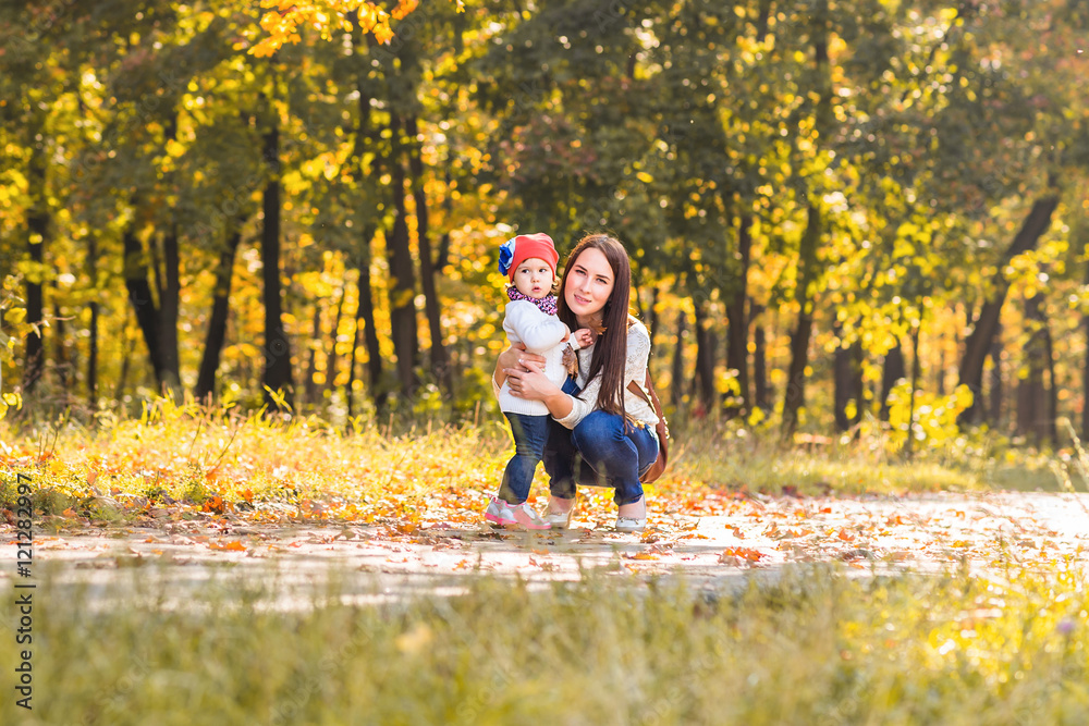 Fototapeta premium Little girl and her mother playing in the autumn park