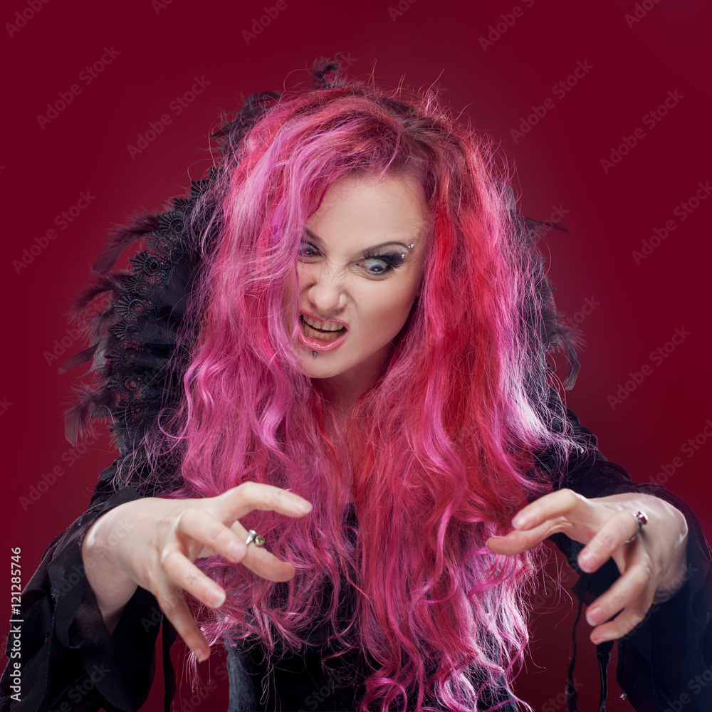Scary witch with red hair performs magic. Halloween. Stock Photo