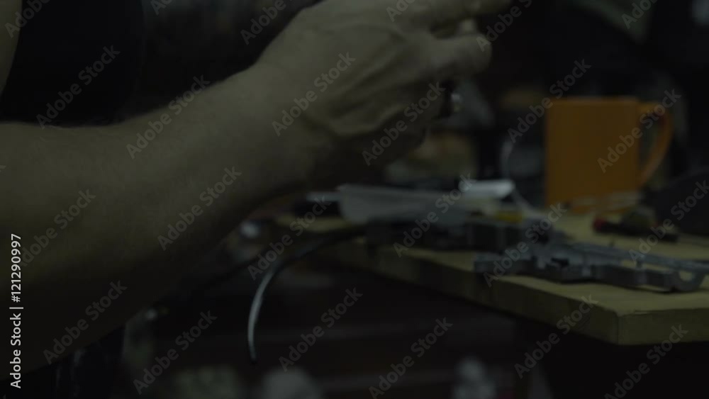 Man repairing weapons. The guy with the beard cleans and repairs armekie rifles and pistols at his desk in the workshop Man repairing weapons. The guy with the beard cleans and repairs armekie rifles and pistols at his desk in the workshop