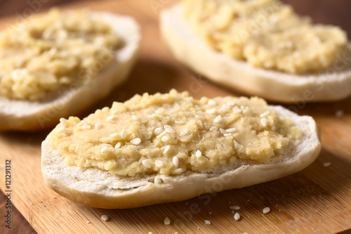 Chickpea spread or hummus on bread sprinkled with sesame seeds, photographed with natural light (Selective Focus, Focus one third onto the first bread)