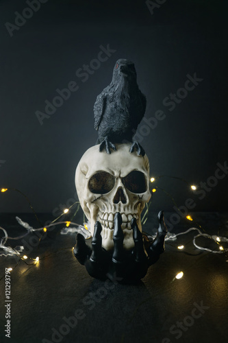  Creepy skull with black bird sitting on skeleton hand photo