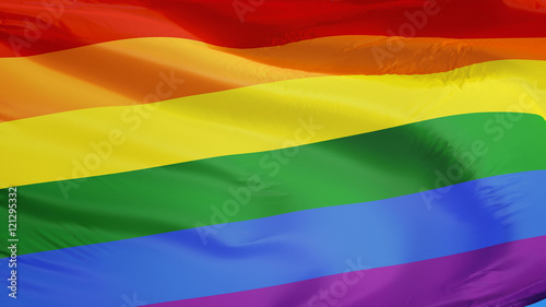 Photographie The gay pride rainbow flag waving against clean blue sky, close up, isolated wit