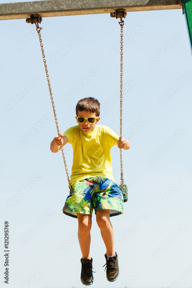 Boy playing swinging by swing-set.