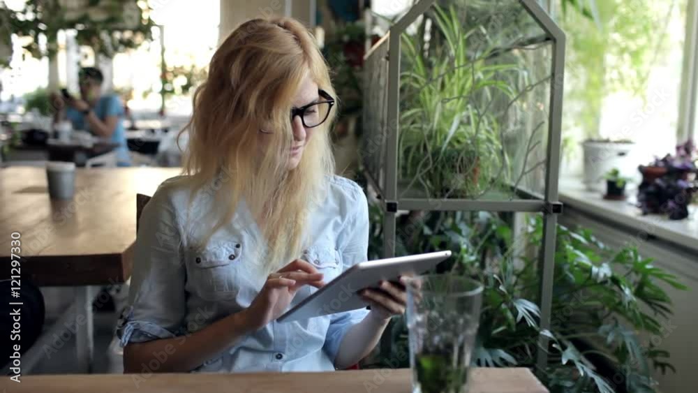 Woman in Glasses Using Tablet at Cafe Woman in Glasses Using Tablet at Cafe