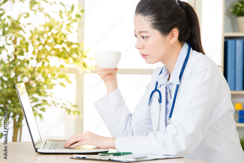 Doctor drinking coffee and using computer, healthcare and medici Doctor drinking coffee and using computer, healthcare and medici