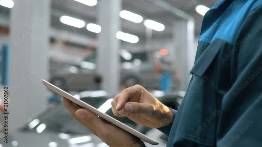 Smiling mechanic using a tablet pc at the repair garage service