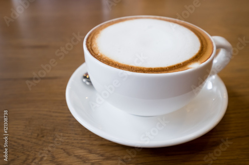 Cup of Cappuccino Coffee with foam on wood table background.