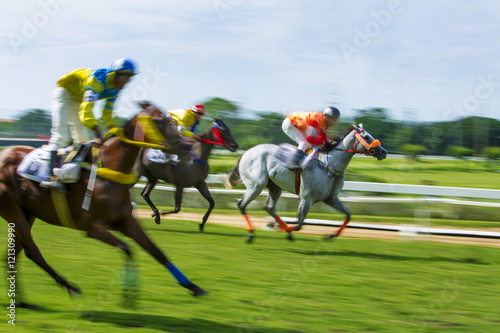Motion blurred Race horses with jockeys on the home straight