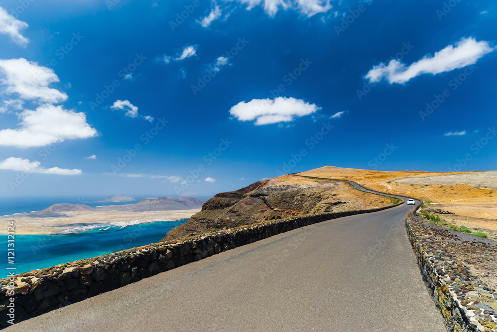 Φωτογραφία The road to the top of the mountain Mirador del Rio on background blue sky