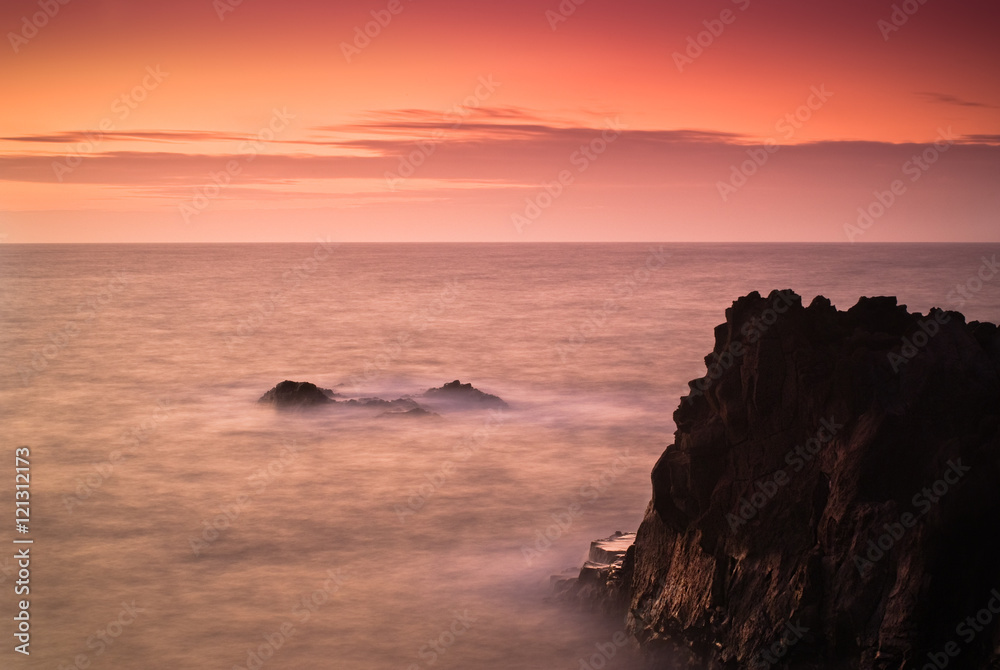 Cliffs of Los Hervideros in the oncoming waves and sunset light on a long exposure. Lanzarote. Canary Islands. Spain