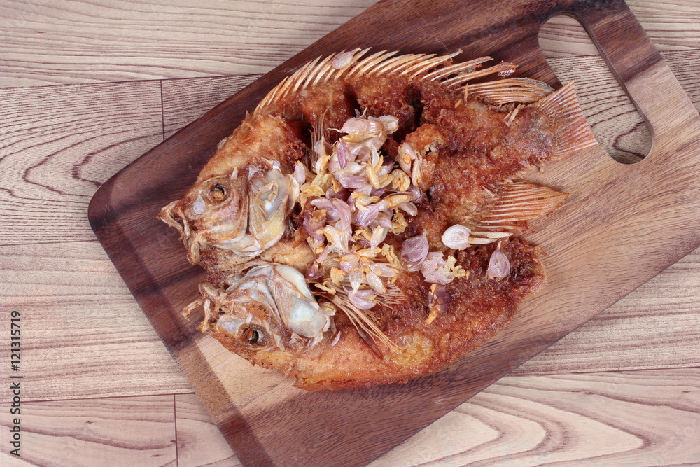 Deep fried fish ,Nile tiapia, with crispy garlic on butcher served. Top view. Deep fried fish ,Nile tiapia, with crispy garlic on butcher served. Top view.