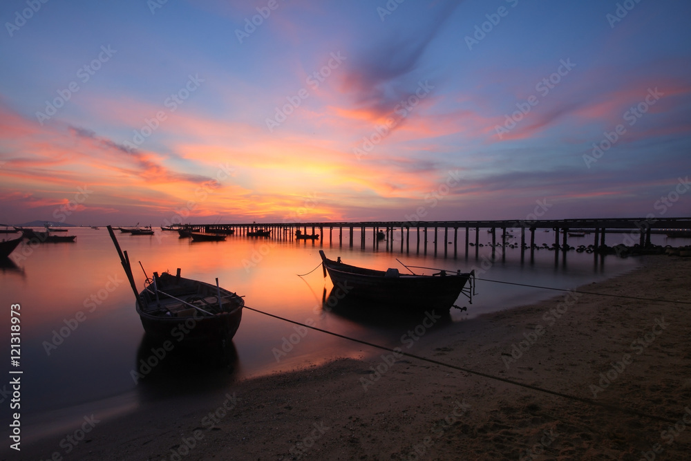 Silhouette natural background of small fishing boats moored beached on the beach during time the sunset and the beautiful natural of the colorful sky at Bang Phra beach , Chonburi province in Thailand