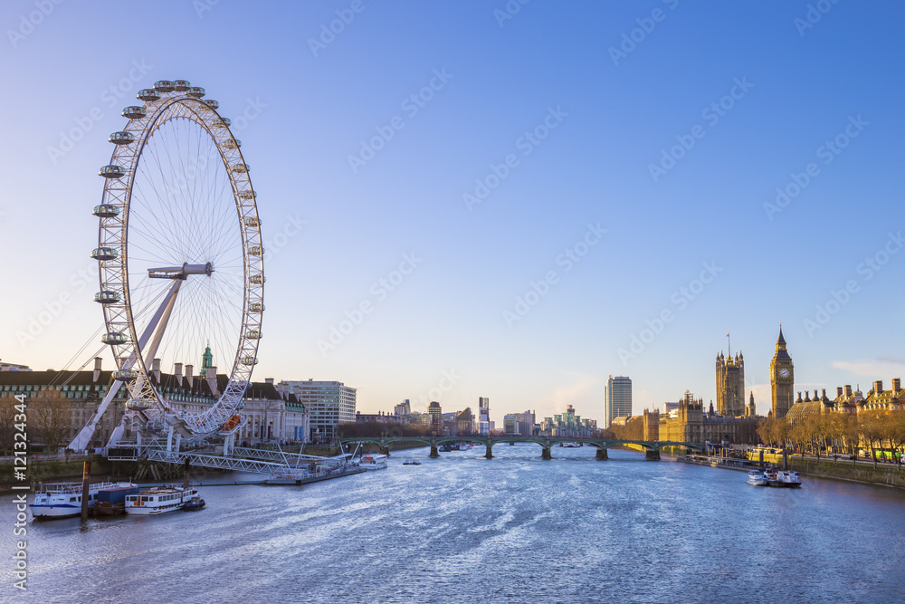 London skyline view at sunrise with Big Ben, Houses of Parliament and ships on River Thames with clear blue sky - England, UK