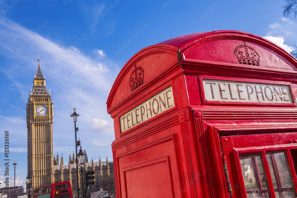 Obraz premium London, UK - Iconic British red telephone box with Big Ben and Double Decker bus at background on a sunny day with blue sky