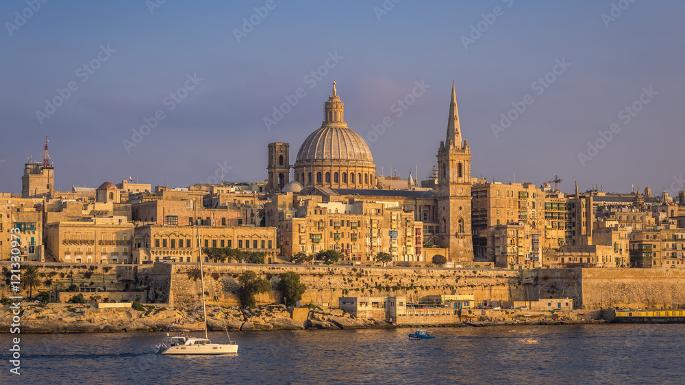 Valletta, Malta - Sailboat and the famous St.Paul's Cathedral with the ancient city of Valletta at sunset
