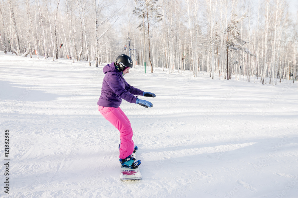 Girl in purple jacket and pink pants learn ride a snowboard