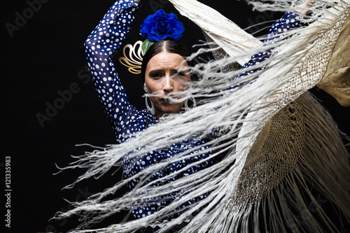 Young flamenco dancer in beautiful dress on black background.