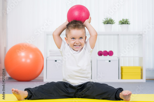 kleiner junge macht gymnastik mit dem ball