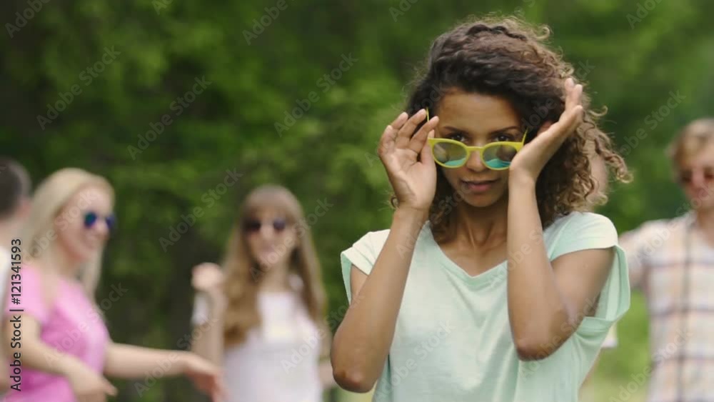 Pretty woman in sunglasses dancing with friends at summer camp, youthfulness Pretty woman in sunglasses dancing with friends at summer camp, youthfulness