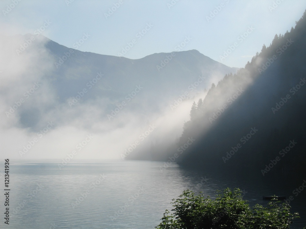 Early morning mist hanging over Brienzersee Lake, Switzerland, with mountains in the distance Early morning mist hanging over Brienzersee Lake, Switzerland, with mountains in the distance