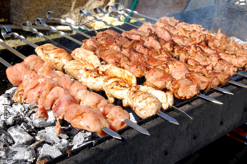 Grilling marinated shashlik on a grill. Shashlik is a form of Shish kebab  popular in Eastern, Central Europe and other places. Shashlyk (meaning  skewered meat) was originally made of lamb. Stock Photo