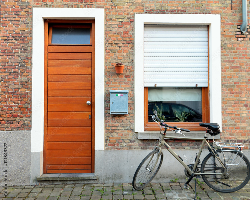 Typical european old street - 	pebble pavement, wooden door of apartment and bicycle.