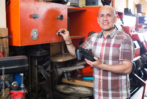 Workman repairing pair of shoes . photo