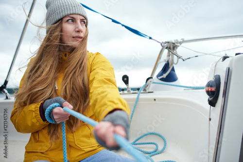 Young woman pulling rigs on the sailboat photo