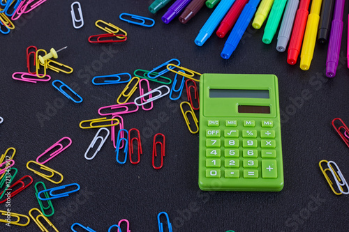 calculator, paper clips, markers on black Board