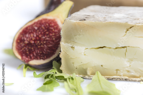 Tasty cheese piece with figs and green salad decoration on a kitchen