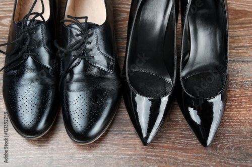 Two different Pairs   of black classic modern shoes on the woode © Saklakova