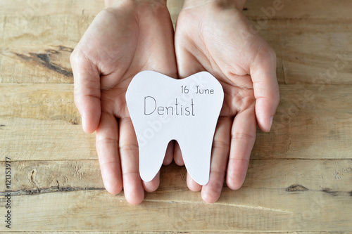 dentist appointment in paper cuts tooth shape in woman hand
