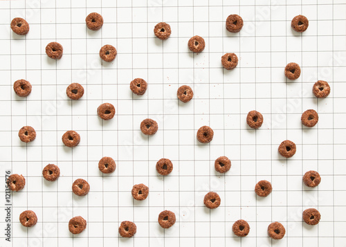 Top view of chocolate cereal pattern on grid pattern background.