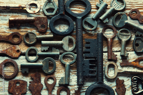 Many rusty keys and padlocks on white wood