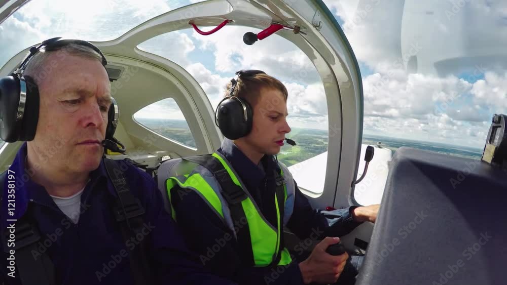 Time lapse with cockpit view of middle aged flight instructor sitting alongside student pilot and mentoring him on his first flight 