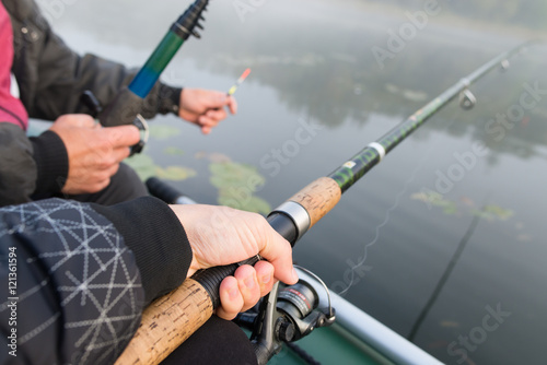 Close-shot of human hands holding a fishing-rod on the foregroun