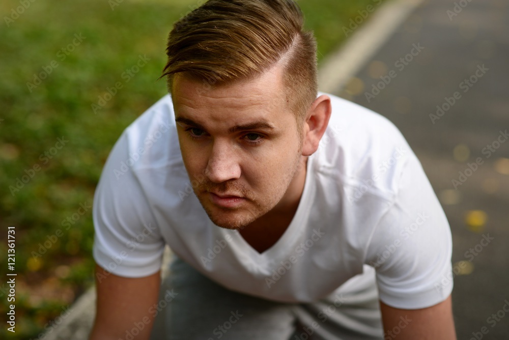 Blond man getting ready to run on a running track Blond man getting ready to run on a running track