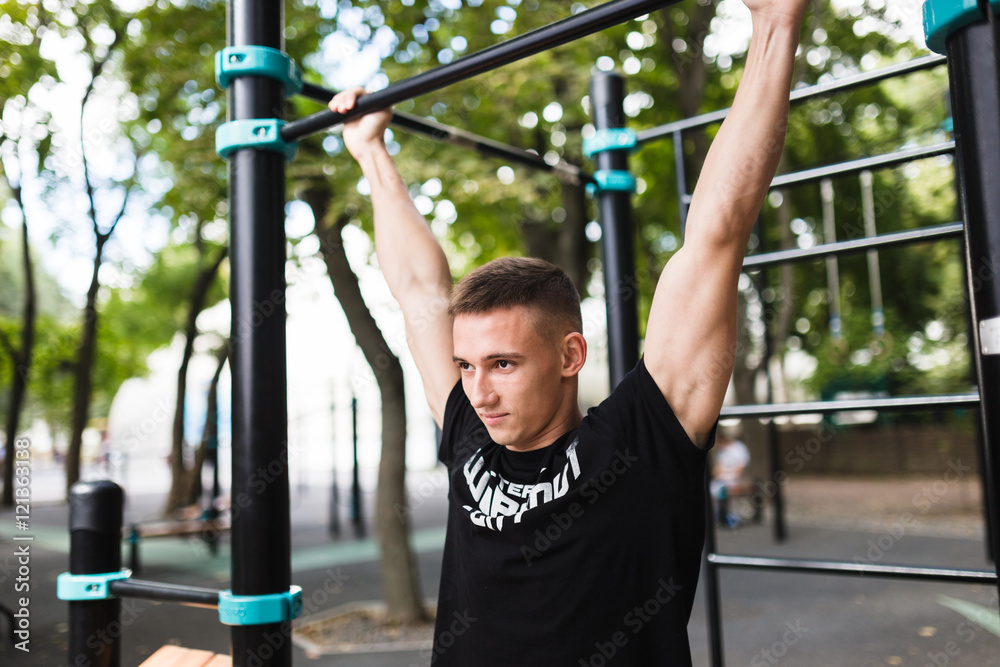 Young man doing pull ups on horizontal bar outdoors, workout, sport concept Young man doing pull ups on horizontal bar outdoors, workout, sport concept