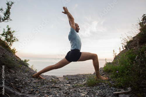 man doing yoga on the stone nearby ocean