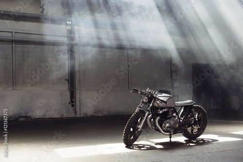 motorcycle standing in dark building in rays of sunlight