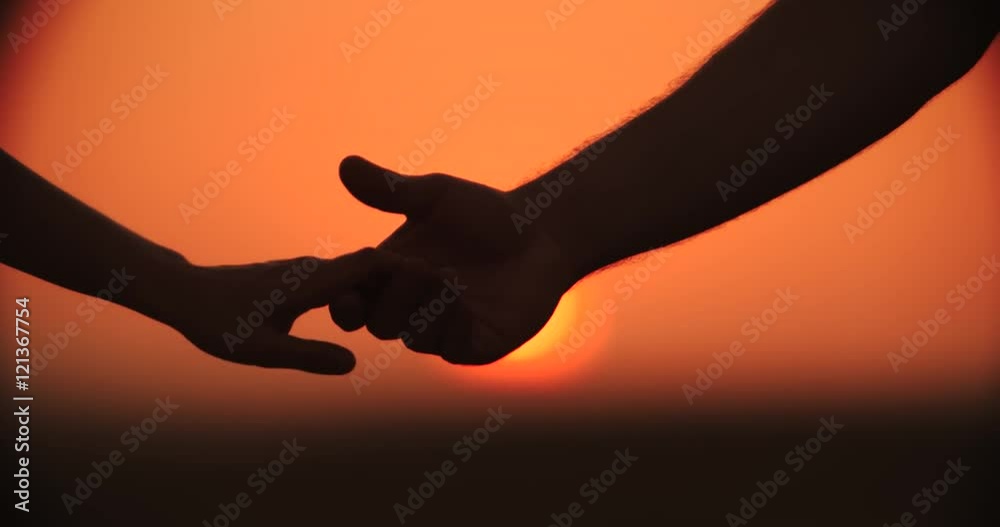 4k,Close up of the hands of a romantic couple holding hands at sunset silhouetted, slow motion