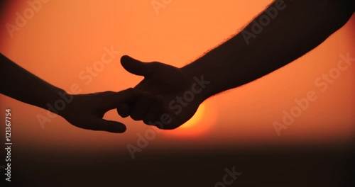 4k,Close up of the hands of a romantic couple holding hands at sunset silhouetted, slow motion