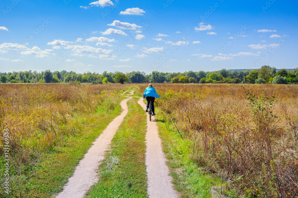 Girl walking with bicycle on the rural road