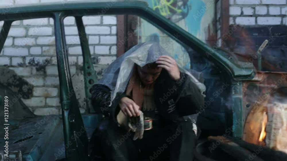 Homeless man sitting in old car in the rain. Homeless man sitting in old car in the rain.