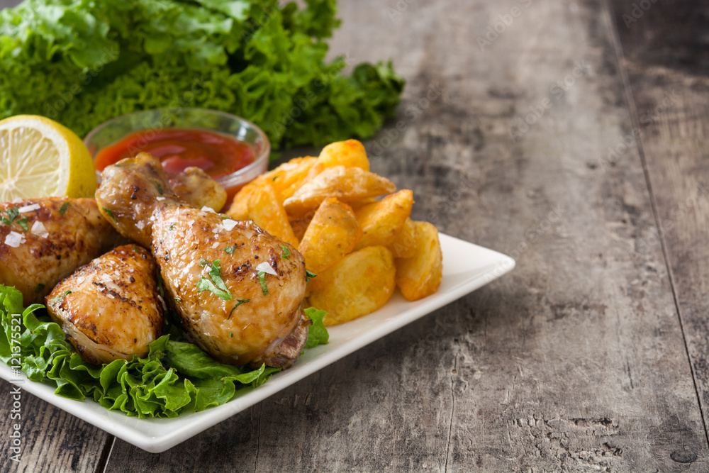 Roast chicken drumsticks and chips on wooden table
Roast chicken drumsticks and chips on wooden table