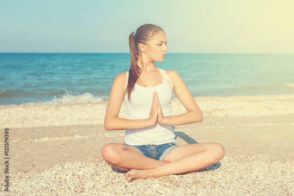 young woman practicing yoga or fitness at seashore