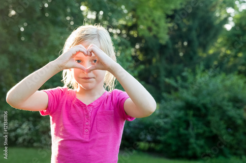 Young Girl Looking Through Heart Hands