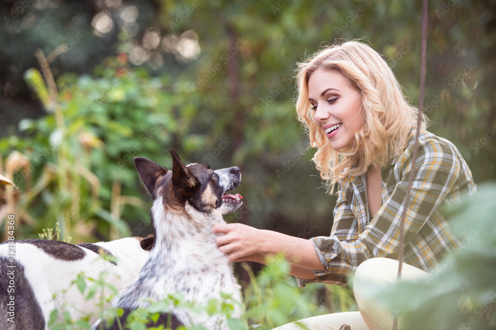 Beautiful blond woman with dog in green garden Beautiful blond woman with dog in green garden