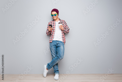 Full portrait of hipster man holding cup of coffee and typing sm