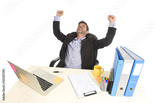 young attractive businessman happy doing fist victory sign sitting at office computer desk celebrating